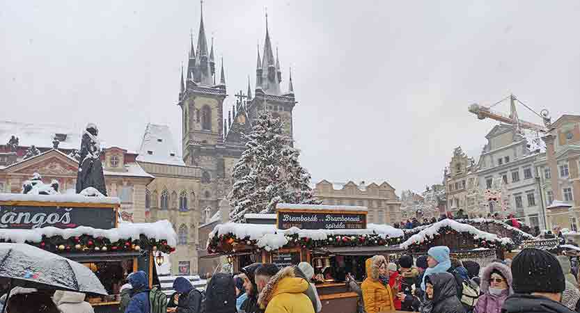 Mercado de Navidad lleno de nieve de la Ciudad Vieja de Praga con el árbol delante iglesia del Tyn